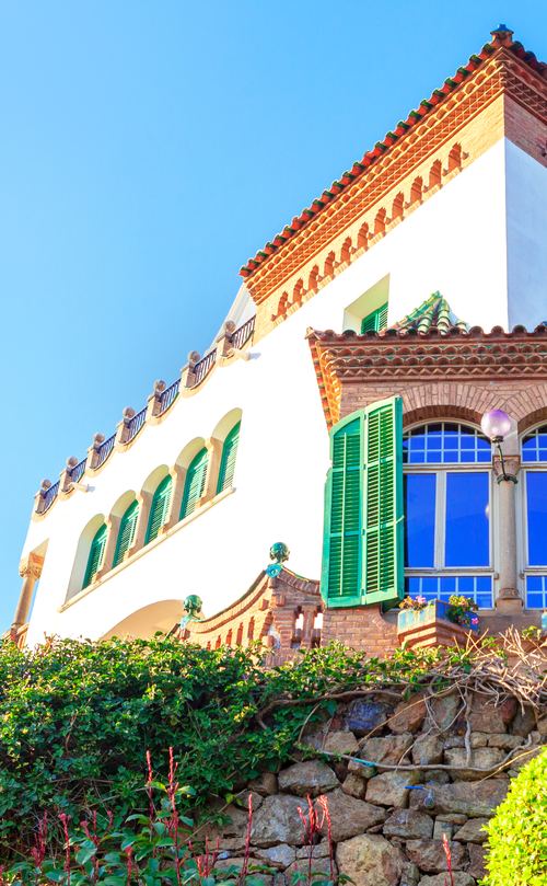 A white Spanish villa with green shutters and a terracotta roof